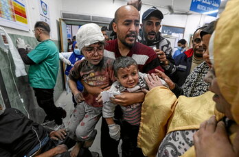 En el hospital Al-Najar, un hombre lleva a dos niños heridos en un bombardeo en Rafah.