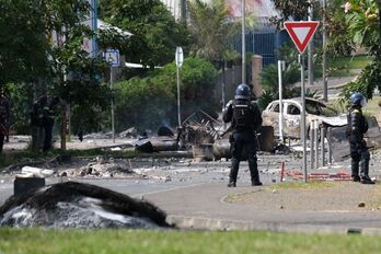 Agentes de la Gendarmerie junto a vehículos quemados para ser usados como barricada. 